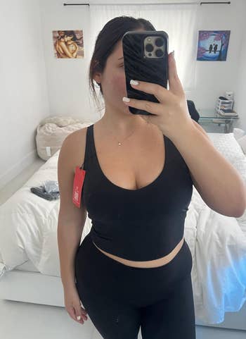 Person successful  a reflector  selfie wearing a fitted vessel  apical  and leggings, with a disposable   covering  tag. Room inheritance  partially visible