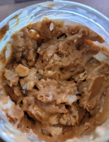 The open jar of peanut butter showing candy inside 