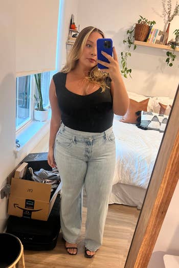 Peninjau mengenakan bodysuit hitam dengan jeans