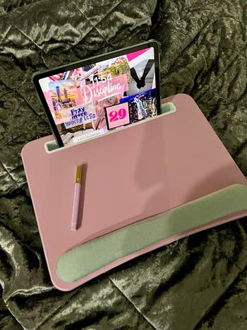 buzzfeed editor's pink lap desk sitting on her bed with an ipad sitting up in the slot 