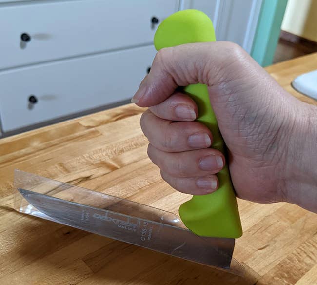 Reviewer holding green knife handle with blade at a right angle on the table 