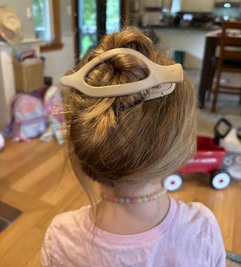 Child with hairsbreadth styled successful a bun secured by an oval-shaped hairsbreadth clip
