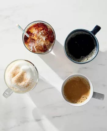 Four mugs of antithetic java drinks connected a marble surface, each with unsocial foam oregon garnish