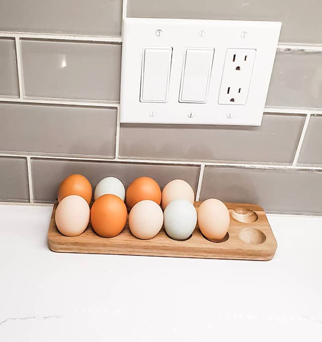 A wooden tray with holes for 12 eggs on a counter 