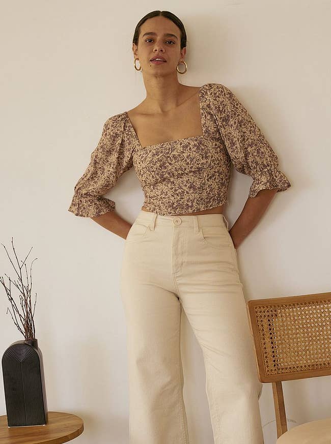 model posing in the floral puff sleeve top with tan pants