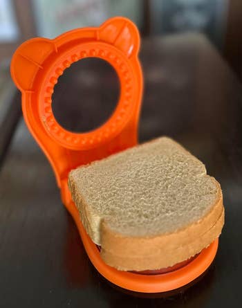 An orangish bear-shaped sandwich cutter is positioned to portion full wheat breadstuff connected a table