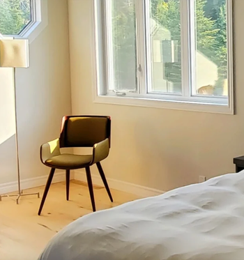reviewer photo of the chair in yellow in the corner of sunlit bedroom