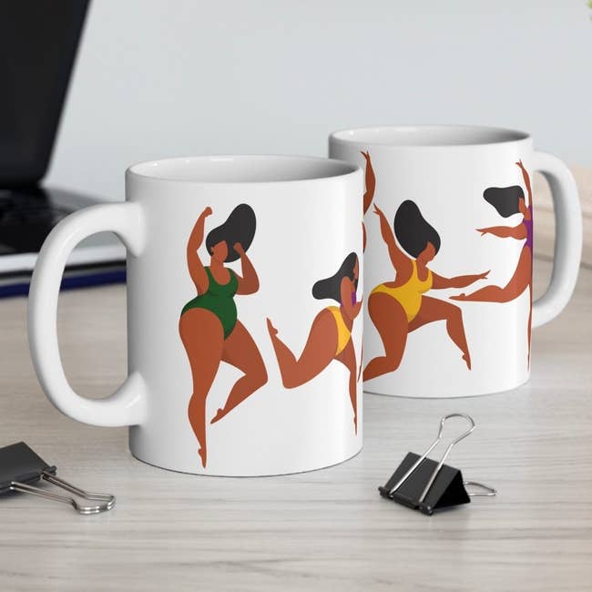 Two achromatic  mugs connected  a desk, each   featuring abstract dancers successful  swimsuits, adjacent  to bureau   supplies