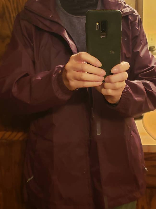 Person taking a reflector  selfie wearing a hooded overgarment   indoors, showcasing its acceptable  and style
