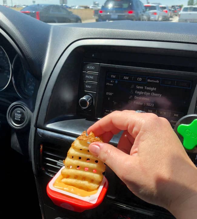 reviewer dunking a french fry in sauce being held by the dip clip