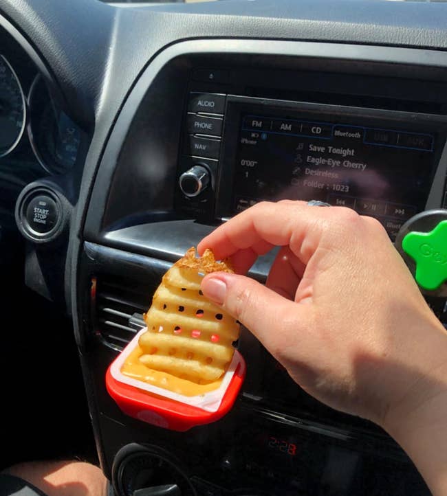 reviewer dunking a french fry in sauce being held by the dip clip
