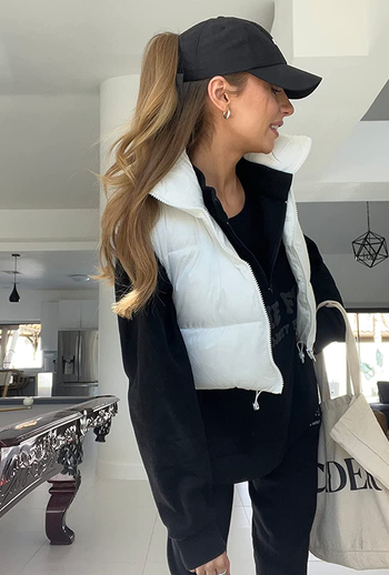 reviewer wearing the white vest with a black top and pants