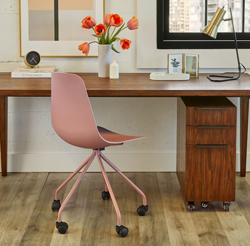 the chair in light pink in front of a desk 