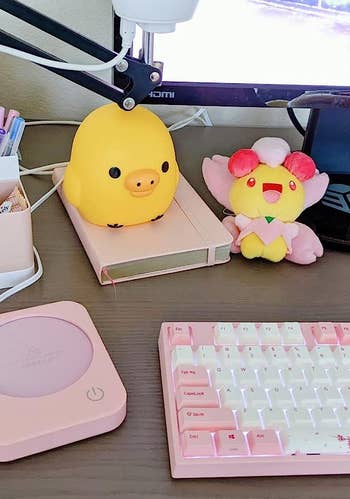 a reviewer's pink mug warmer on a desk next to an assortment of other pink items