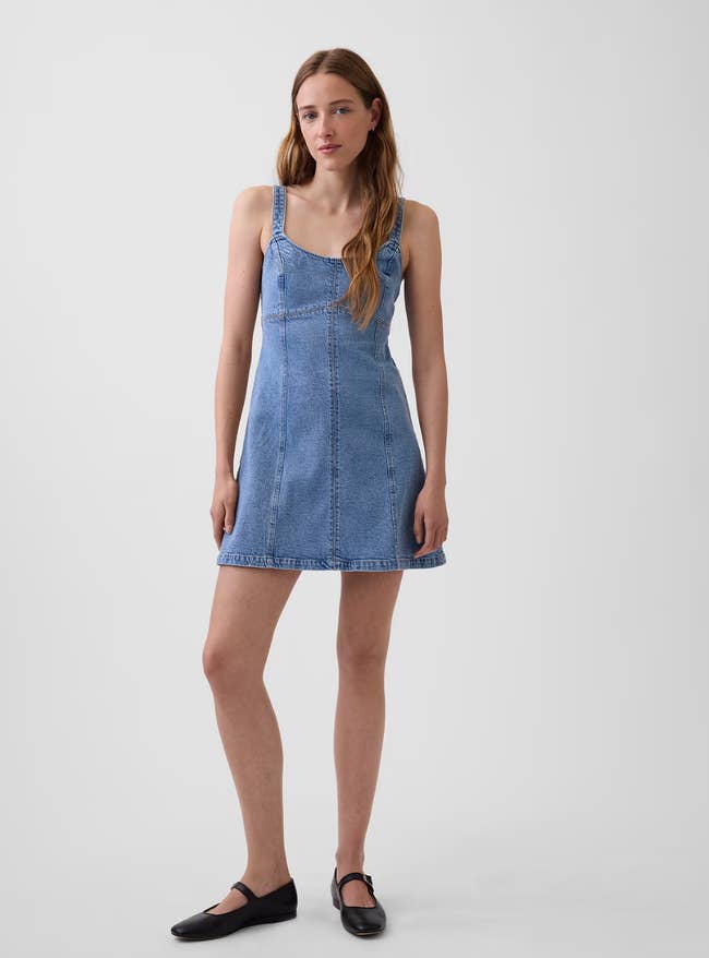 Person wearing a casual denim formal  with straps and achromatic  level  shoes, lasting  against a plain background