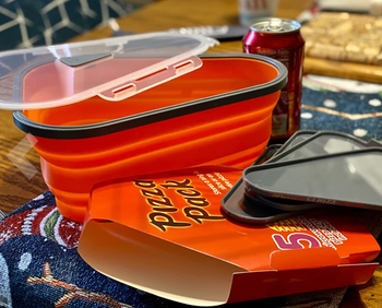 An orange triangular collapsible container with gray dividers