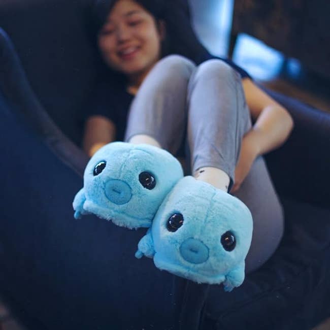 Person lounging with plush blue tardigrade slippers