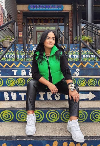 reviewer posing on stairs wearing cropped green vest