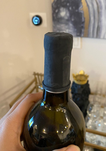 a reviewer photo of one of the wine condoms on a bottle of wine 