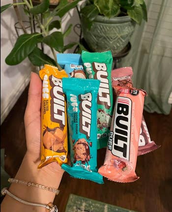 A manus  holds assorted  Built macromolecule  bars, including flavors similar  Salted Caramel, Cookie Dough, and Strawberry, displayed successful  a casual location  setting