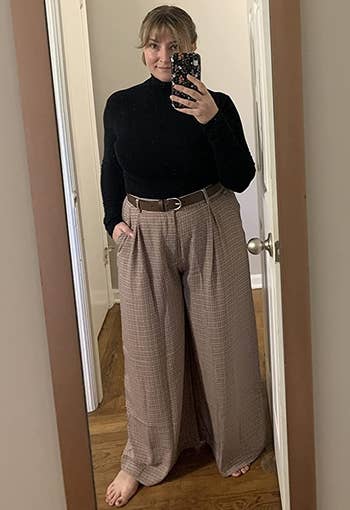 reviewer wearing the multicolored checkered pants with a black turtleneck