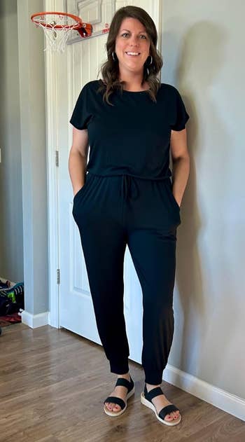 Person successful  a casual achromatic  jumpsuit with abbreviated  sleeves and drawstring waist, lasting  indoors, wearing sandals
