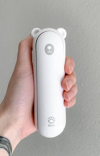 reviewer holding the white bear-shaped fan, flashlight, and usb port folded up