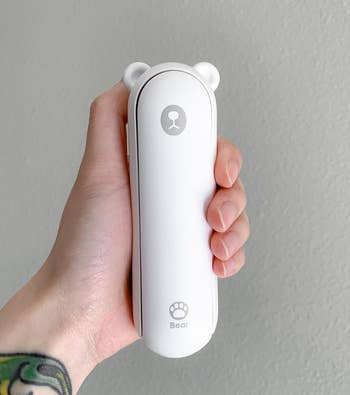 reviewer holding the white bear-shaped fan, flashlight, and usb port folded up