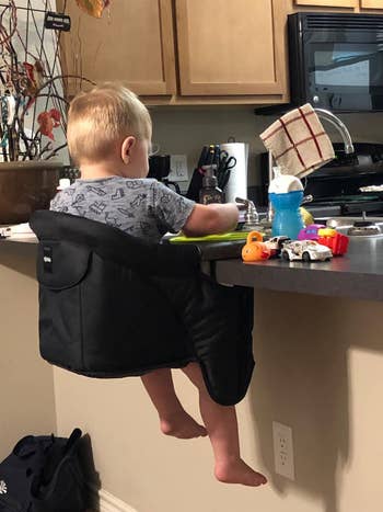 reviewer's photo of a child in the chair attached to the kitchen counter