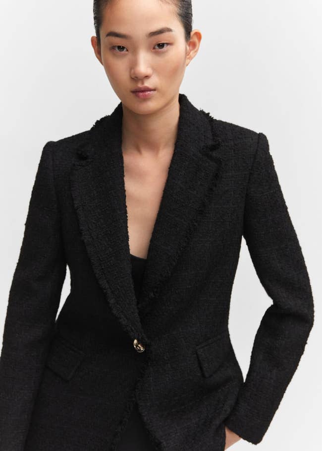 a model in black blazer showing the gold button