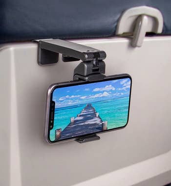 the phone mount attached to a stowed seat back tray and holding a phone