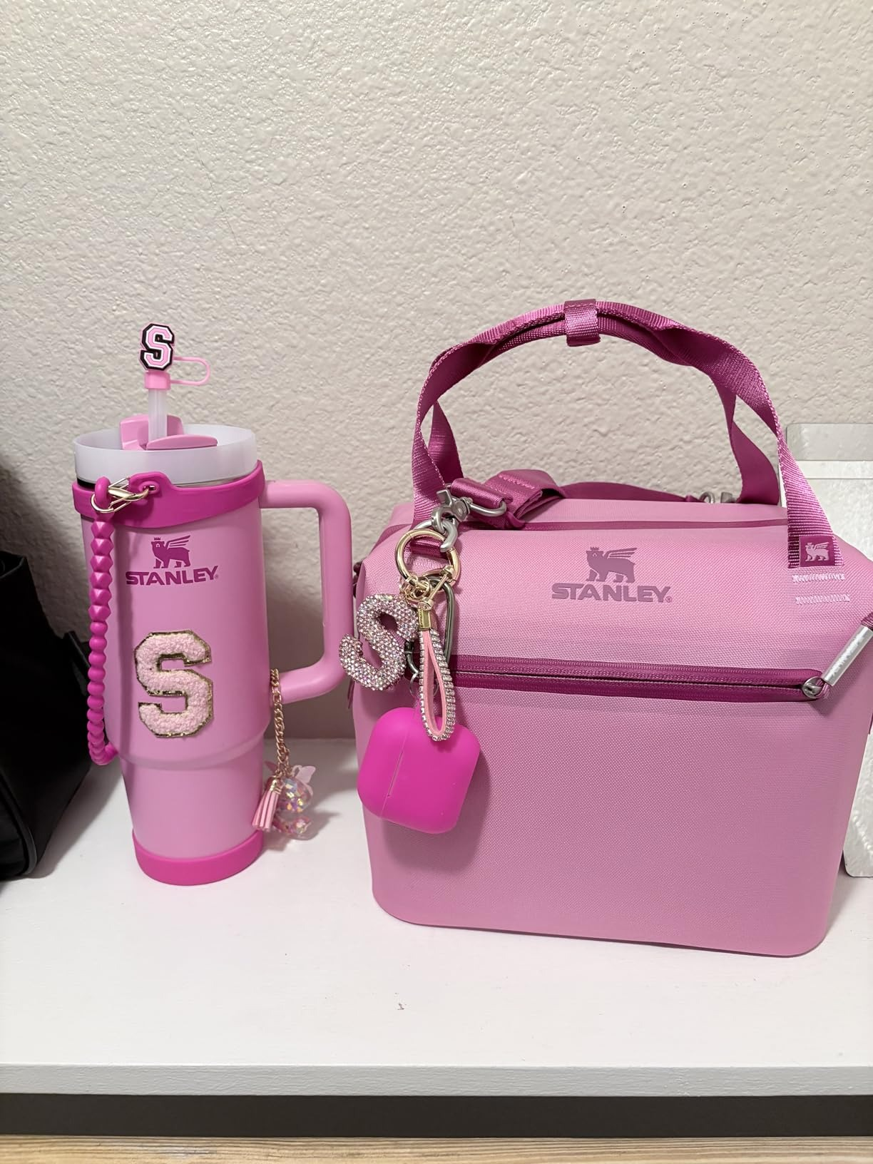Stanley brand pink tumbler and lunchbox with keychains, featuring glittery letter 
