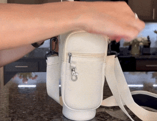 Person puts cell phone and cards into water bottle bag on kitchen counter