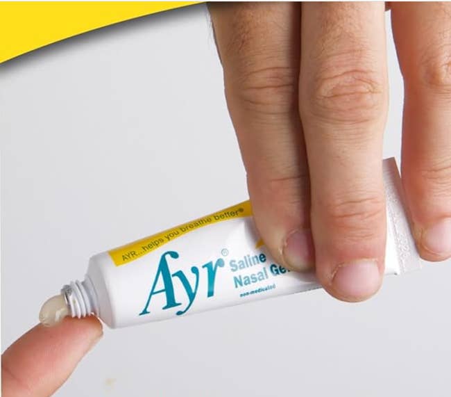 Hand squeezing Ayr Saline Nasal Gel onto fingertip for application