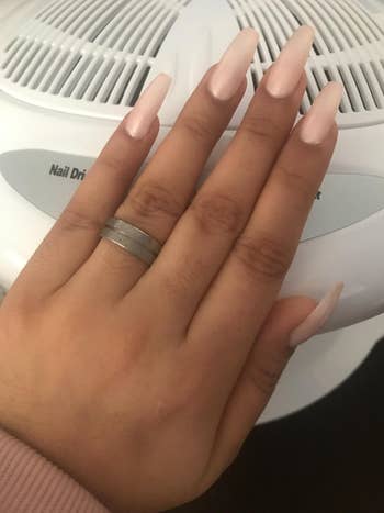 reviewer photo of their long light pink nails above a white dryer