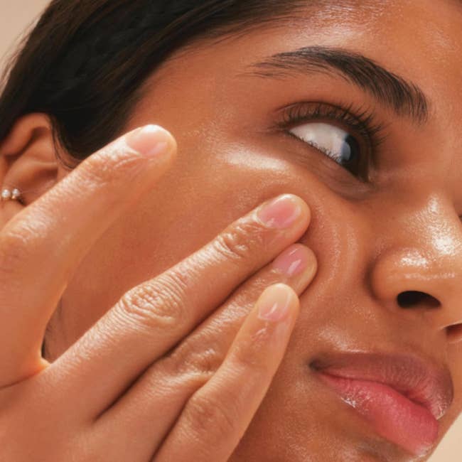 Close-up of a model applying product on cheek
