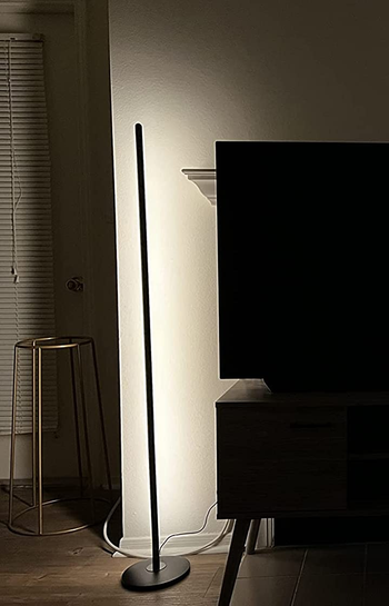 Reviewer image of product next to television and silver stool with white light illuminating