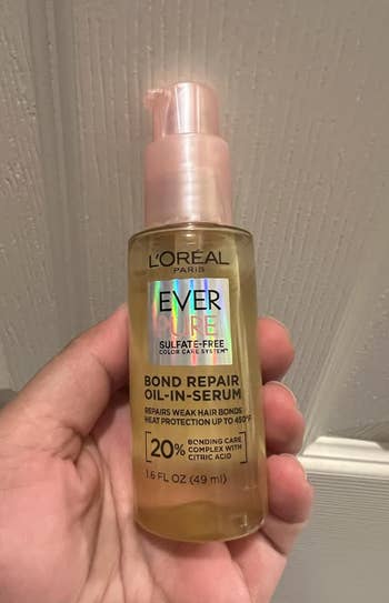A manus  holds a vessel  of L'Oreal Paris EverPure Bond Repair Oil-in-Serum, featuring enslaved  attraction   analyzable  and promising vigor   extortion  up   to 450°F