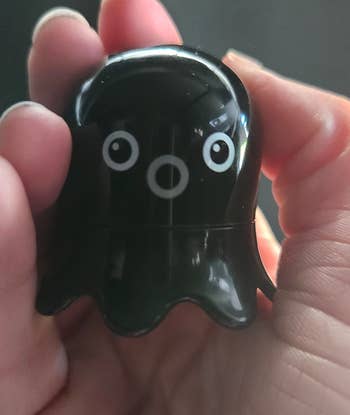 A black small octopus shaped remover in a reviewer's hand 