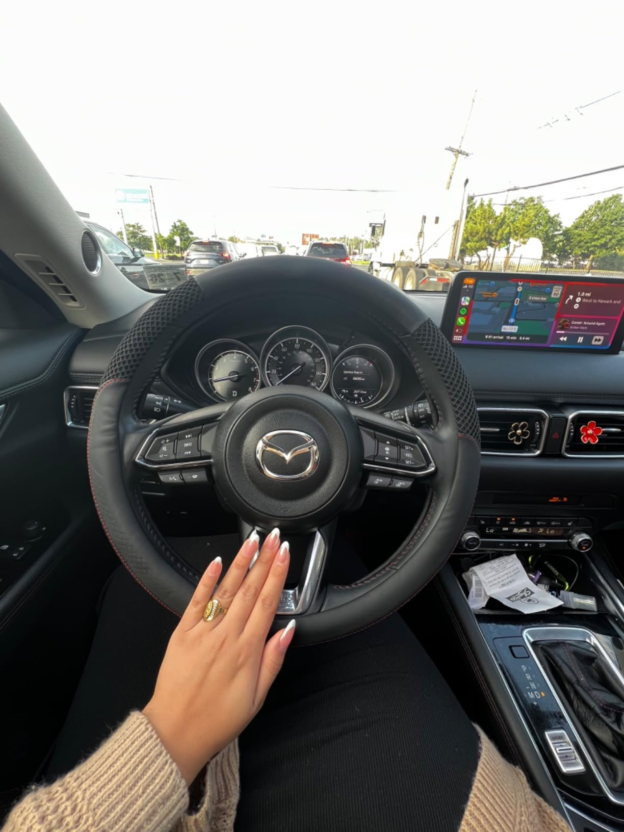 Hand with manicured nails connected  a car   steering wheel