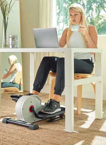 model sitting at their desk and using the elliptical