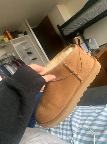 a reviewer holding the short Ugg boot in brown 