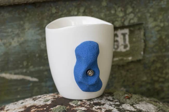 a white mug with a blue climbing hold as its handle