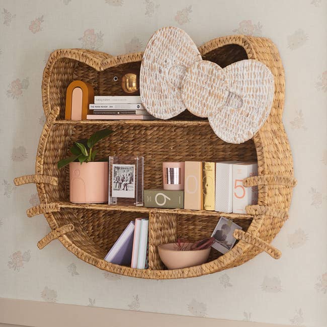 Natural woven bookcase complete with whiskers and bow mounted on a wall