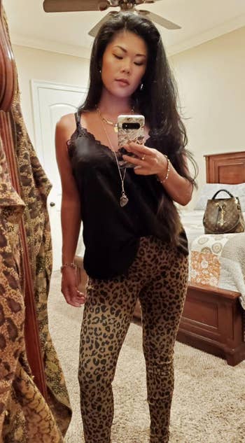 reviewer wearing leopard print knit jeggings with a black tank and jewelry