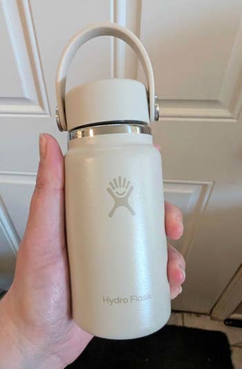 Person holding a beige Hydro Flask vessel  with a handle, perfect  for keeping beverages blistery  oregon  cold