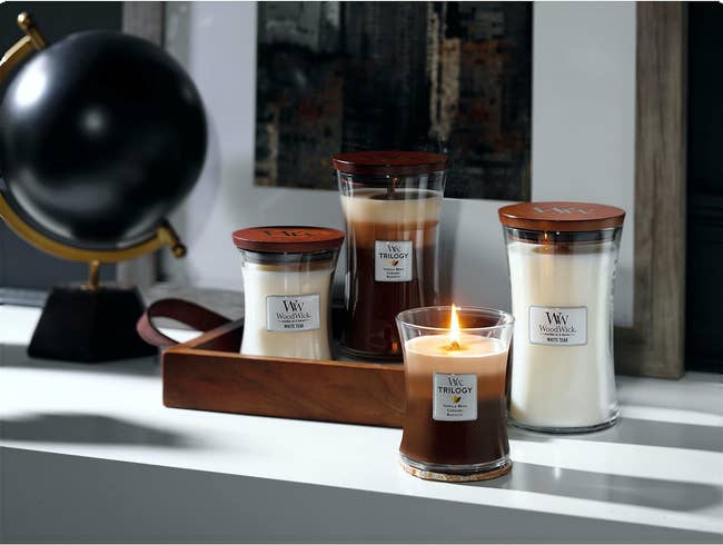 four different woodwick candles on a surface 