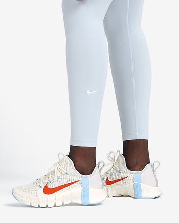 model wearing white training shoes with blue and orange detailing on the sides