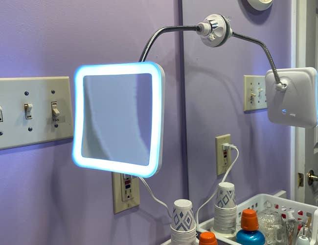a reviewer photo of the gooseneck mirror mounted on a larger bathroom mirror 