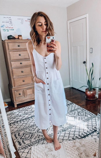reviewer wearing the dress in white, with hands in the pockets